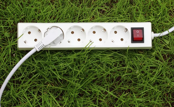 Uma faixa de energia deitada na grama — Fotografia de Stock