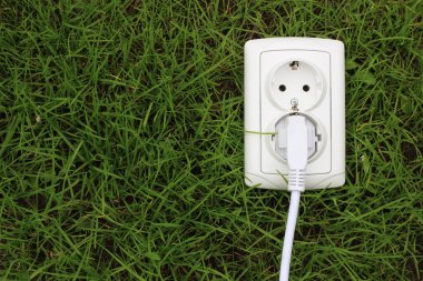 Electric power receptacle on a green grass background clipart