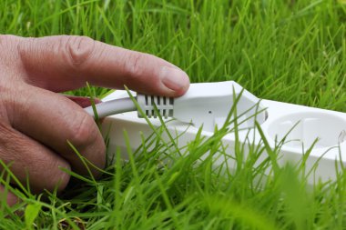 Power strip lying on the grass and hand