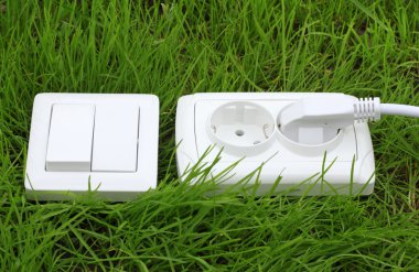 Power receptacle and light switch on a green grass clipart