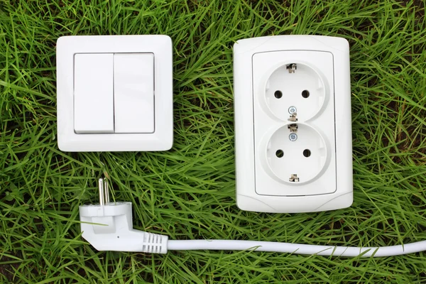 Power receptacle and light switch on a green grass — Stock Photo, Image