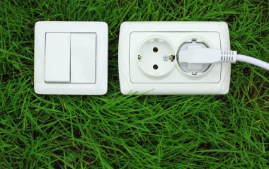 Power receptacle and light switch on a green grass clipart
