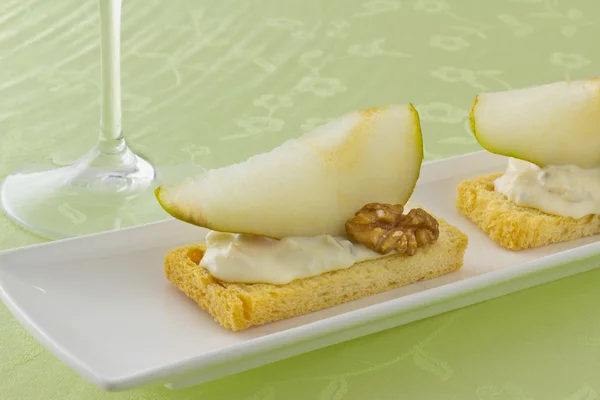 Two canapé with blue chees, slice of pear and walnut