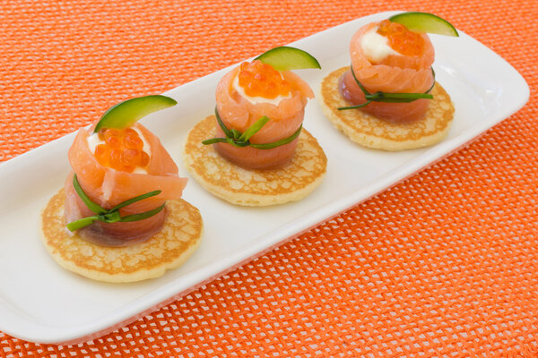 Red salmon roll with chees, caviar and cucumber on” blinis”