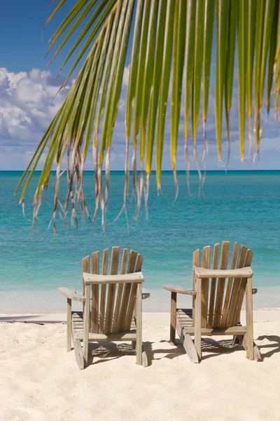 Sedie da spiaggia sulla spiaggia di sabbia bianca con cielo blu e ramo di palma — Foto Stock