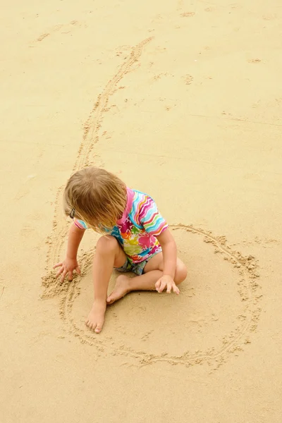 Girl drawing on sand — Stock Photo, Image