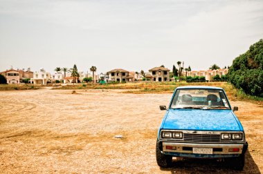 Old car in desolate landscape clipart