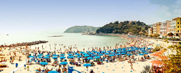 Praia lotada no Mar da Ligúria, Lerici, Itália com guarda-chuvas azuis — Fotografia de Stock