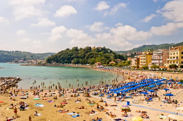 Přeplněné pláže Ligurského moře, lerici, Itálie s modrými deštníky — Stock fotografie