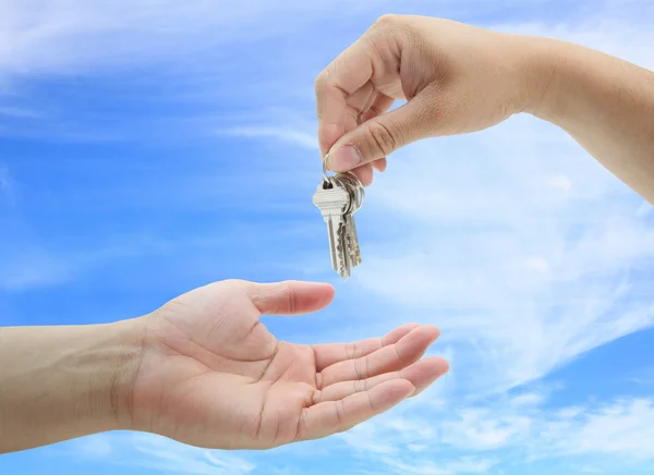 Homem entregando o conjunto de chaves casa contra o céu azul — Fotografia de Stock