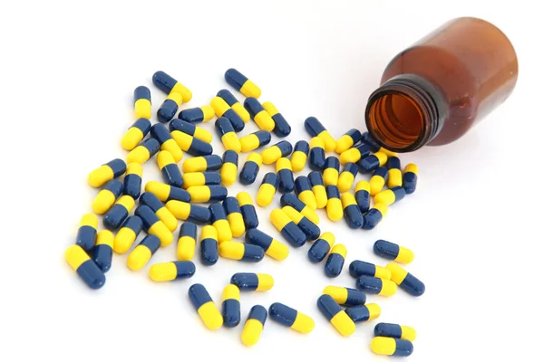 Open pill bottle with capsule spilling out of it — Stock Photo, Image
