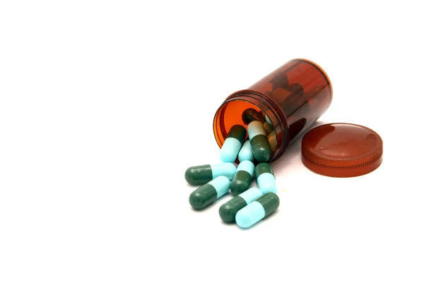 Green capsule spilling out from pill bottle — Stock Photo, Image