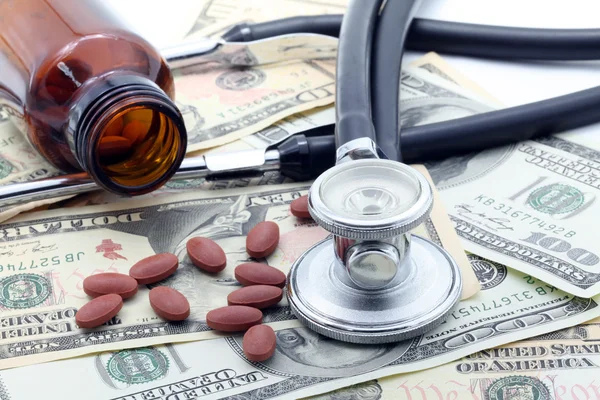 Stethoscope and Pills on dollars — Stock Photo, Image