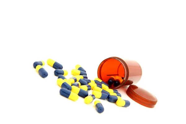 Perspective of isolated capsules spilling out from small bottle — Stock Photo, Image