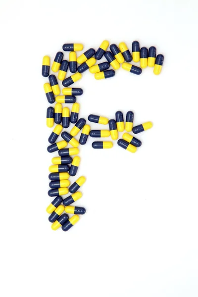 De brief f alfabet gemaakt van medische capsules — Stockfoto