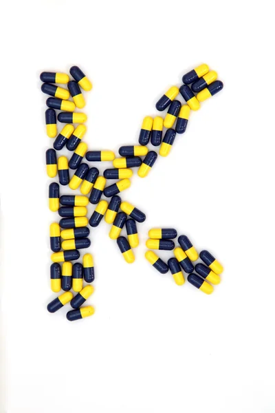 De brief k alfabet gemaakt van medische capsules — Stockfoto