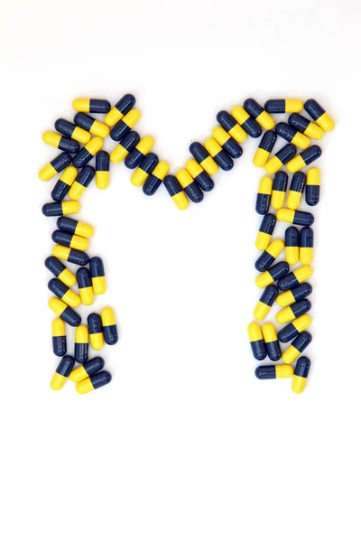 The letter M alphabet made of medical capsules — Stock Photo, Image