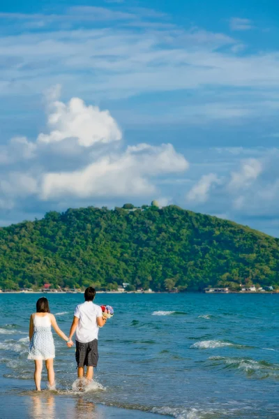 Par walking av hand i hand längs stranden med mild ripp — Stockfoto