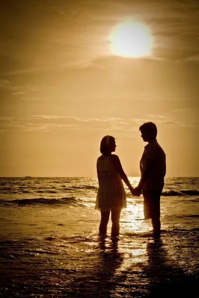 Scena romantica di coppie sulla spiaggia con tramonto — Foto Stock
