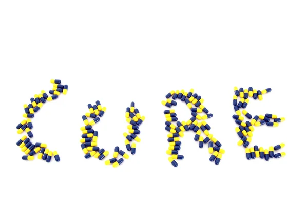 Cuvânt CURE fabricat din capsule galbene albastre — Fotografie, imagine de stoc