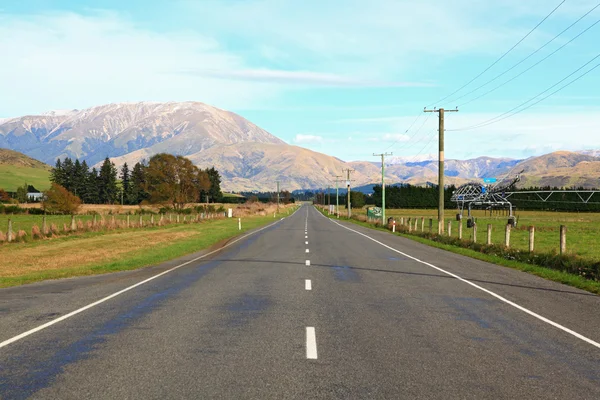 Long road stretching out into the distance with snow mountain ba — Stock Photo, Image