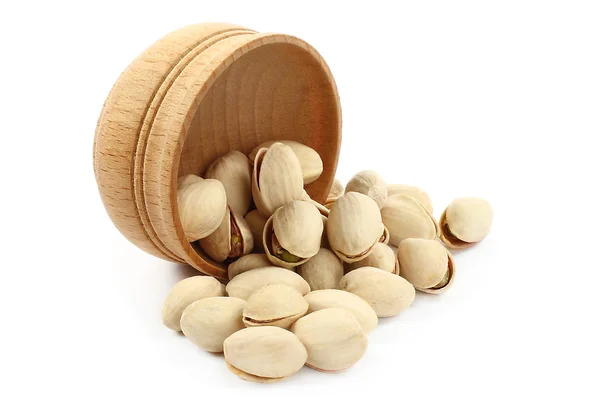 Pistachios pouring out of wooden bowl — Stock Photo, Image