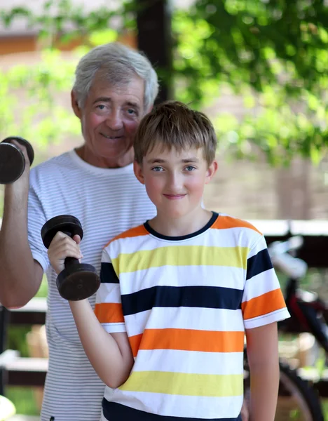 Grootvader en kleinzoon buigen biceps — Stockfoto