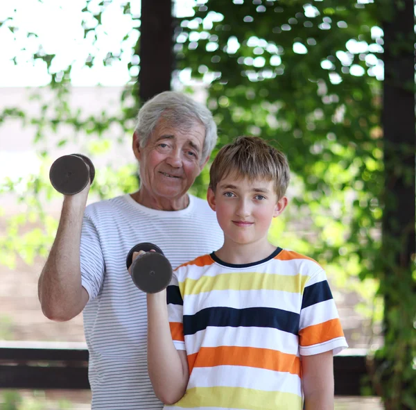 Дедушка и внук сгибают бицепсы — стоковое фото