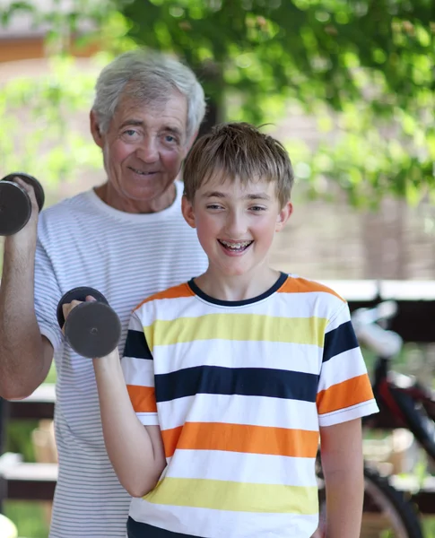Дедушка и внук сгибают бицепсы — стоковое фото