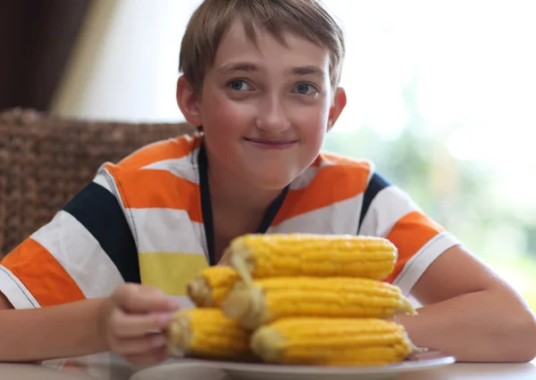 Портрет мальчика за столом с тарелкой кукурузы — стоковое фото