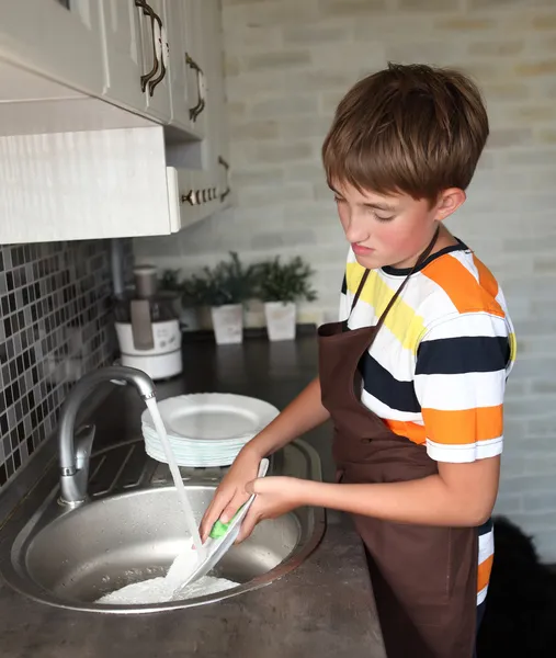 Мальчик моет посуду — стоковое фото
