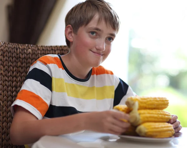 Retrato de um menino na mesa com um prato de milho — Fotografia de Stock