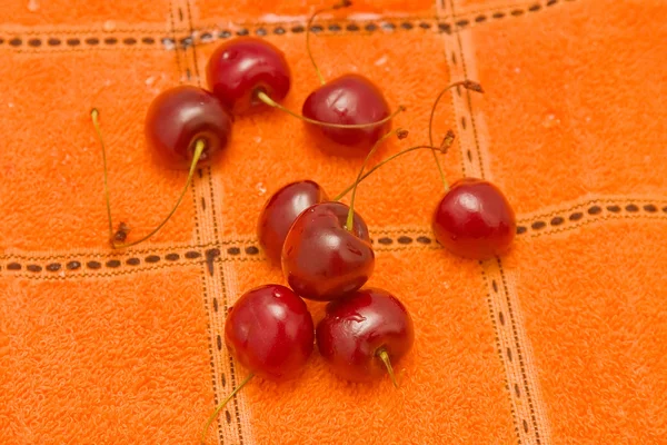 Cherries on orange cloth — Stock Photo, Image