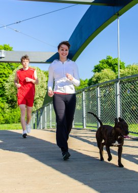 Couple running with dog across the bridge clipart