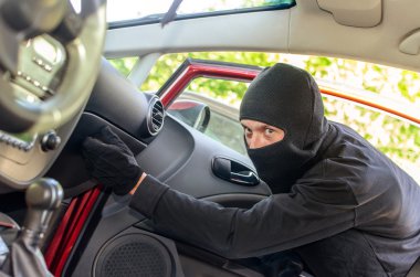 Thief in the mask breaks the door in the car clipart