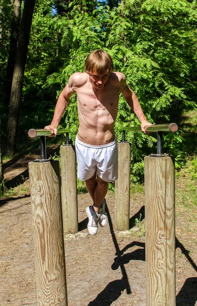 Attractive man pull-ups on a bar in a forest — Stock Photo, Image