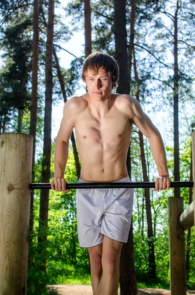 Aantrekkelijke man pull-ups op een balk in een forest — Stockfoto