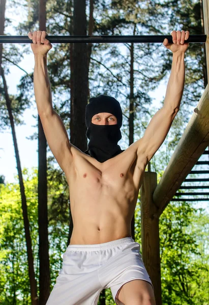 Antiglobalist trains, pull-ups on a bar in a forest — Stock Photo, Image