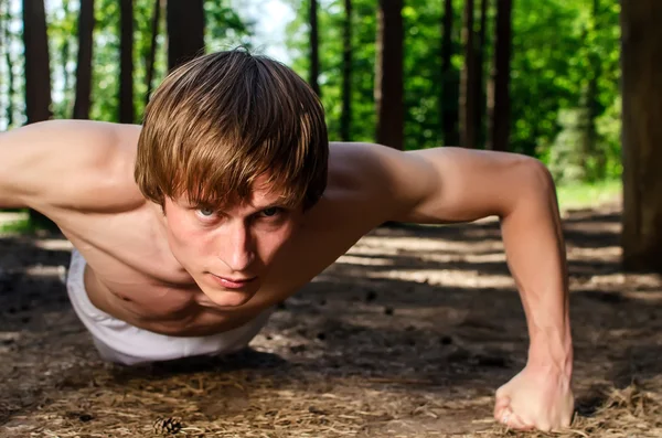 Atraktivní muž dělá push up v lese — Stock fotografie