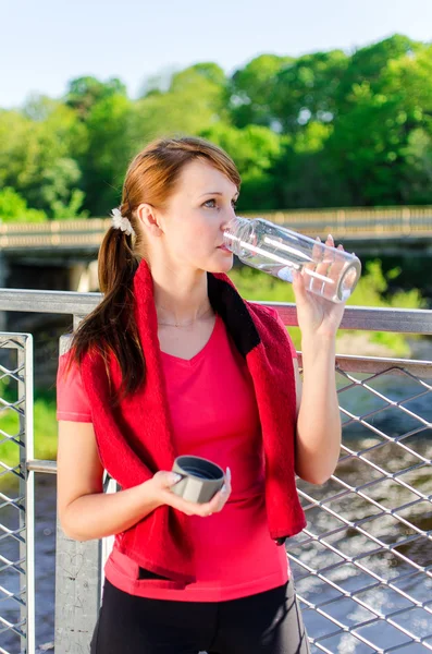 Привлекательная женщина пьет воду на мосту — стоковое фото