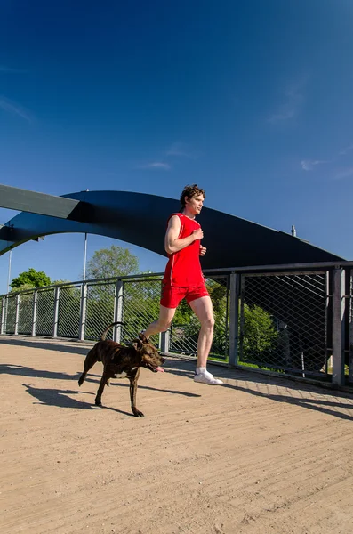 Человек и собака, бегущие на улице — стоковое фото