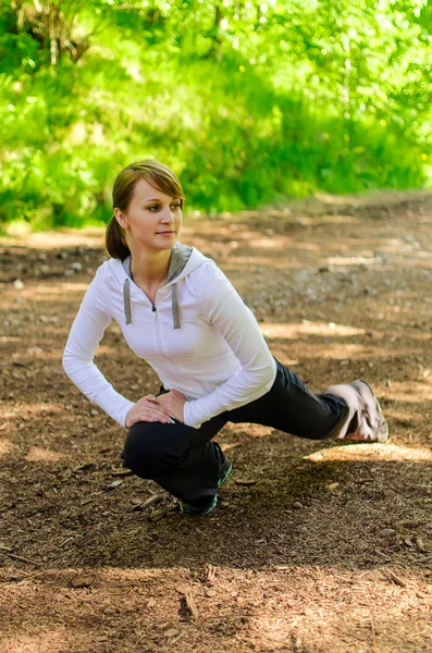 Atractiva joven mujer estirándose antes de correr —  Fotos de Stock