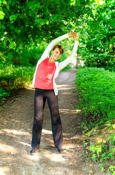 Jovem atraente esticando antes de correr — Fotografia de Stock