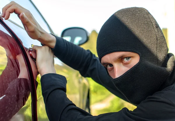 Thief in the mask breaks the door in the car — Stock Photo, Image