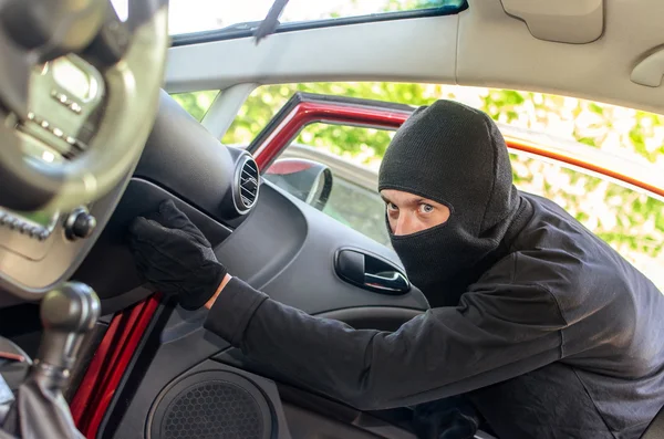 Włamuje się złodziej w masce drzwi w samochodzie — Zdjęcie stockowe