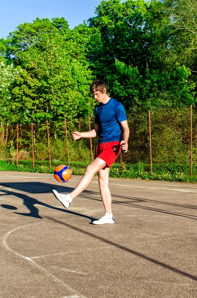 Парень тренируется с мячом на площадке. — стоковое фото