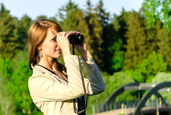 Mujer joven atractiva mirando a través de los prismáticos — Foto de Stock