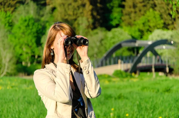 Attractive young woman looking through binoculars — Stock Photo, Image