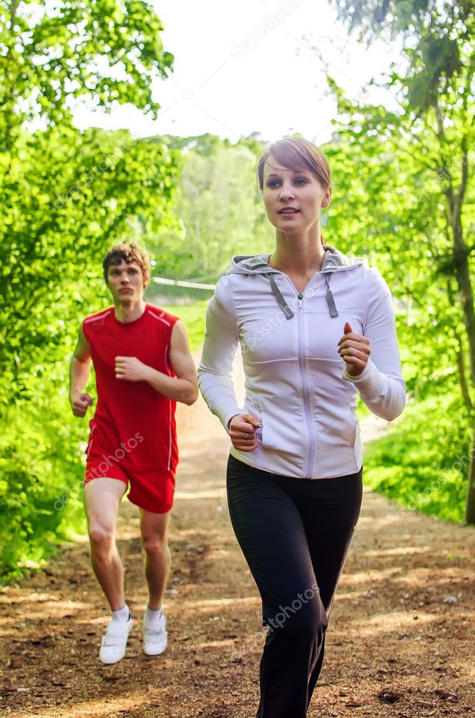 Man and woman running along the forest path