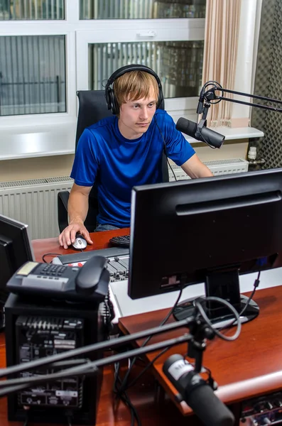 Prezenter siedzi przed mikrofonem w radiu — Zdjęcie stockowe